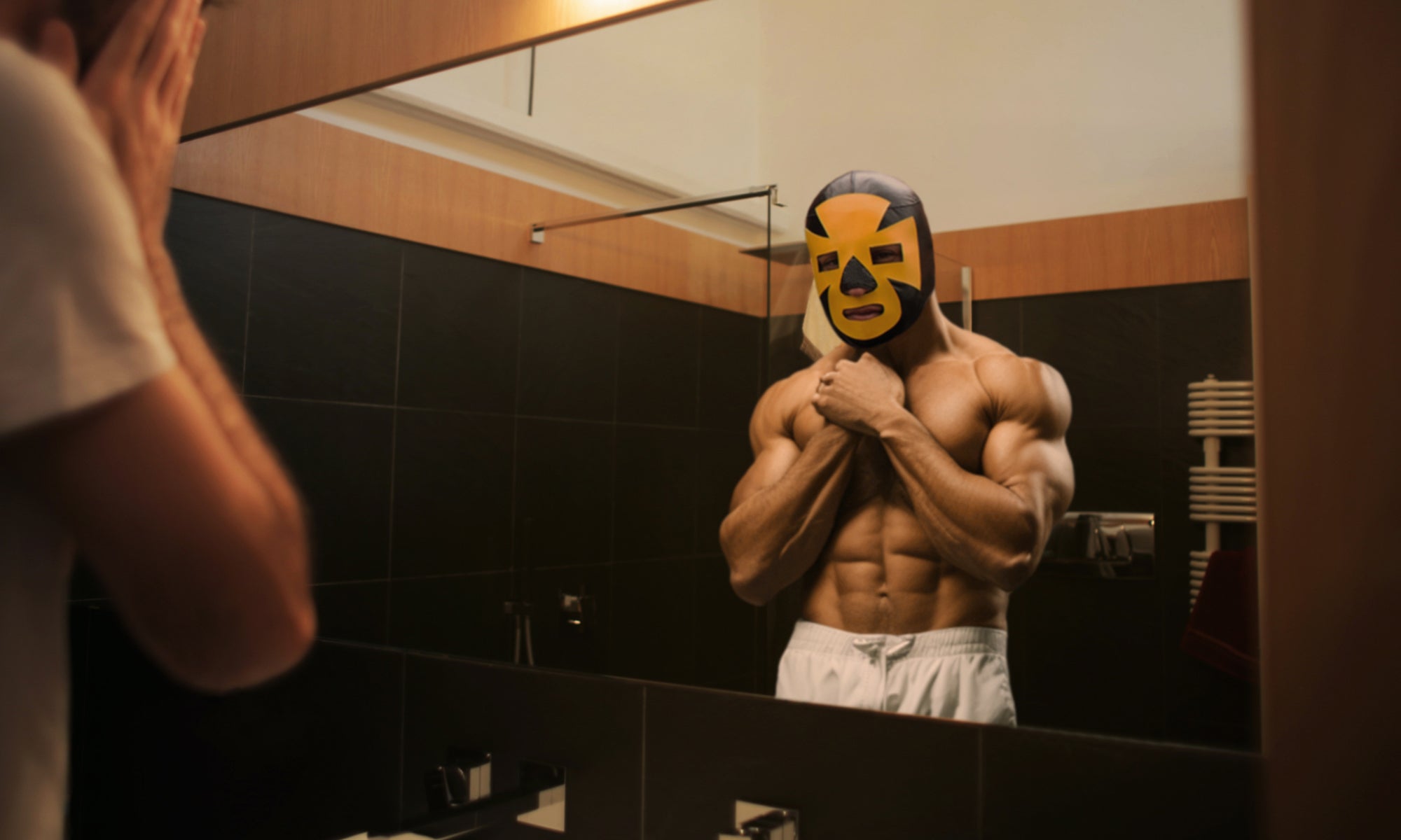 Man Looking in Mirrror Wearing Black & Yellow Espanto Luchador Mask